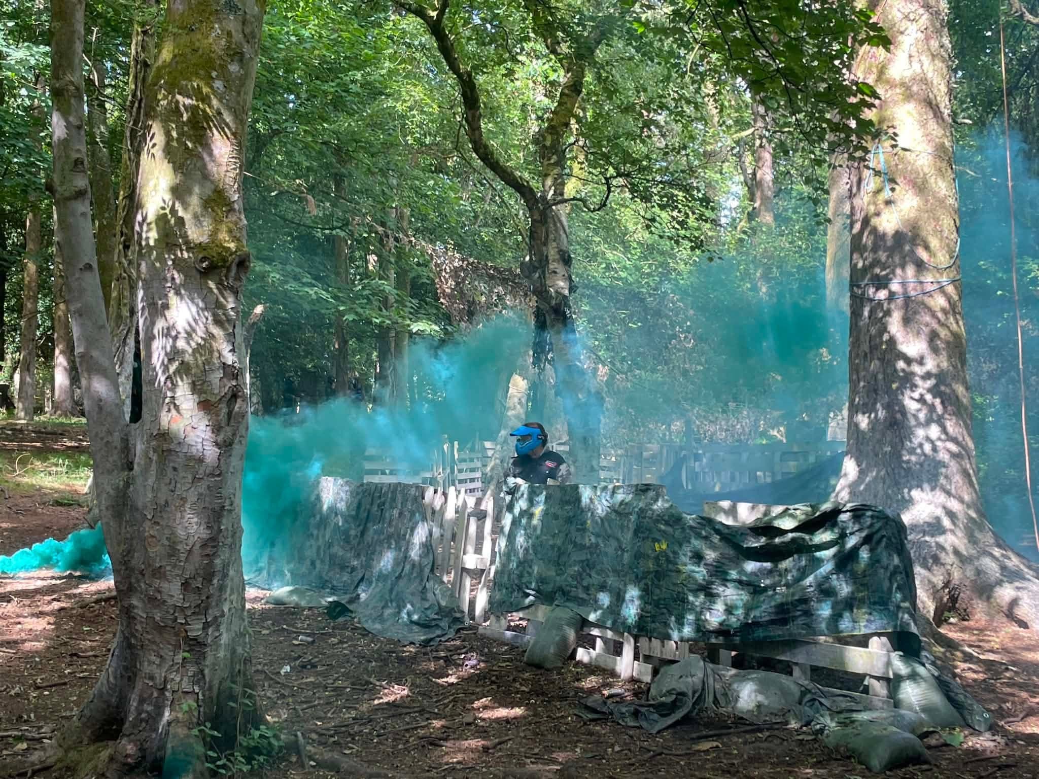 Paintball game underway with blue smoke flares