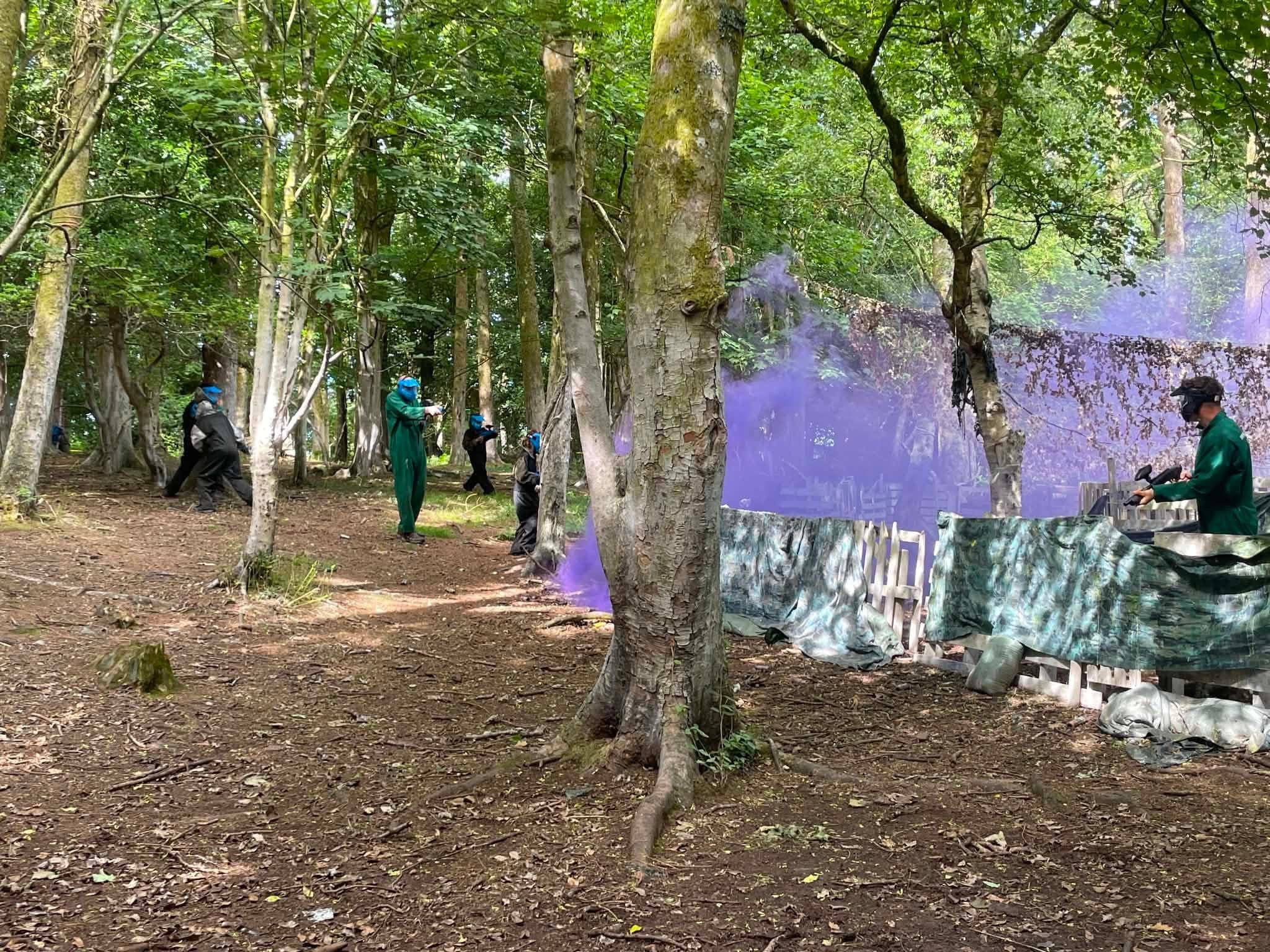 Paintball action with purple flares at an outdoor event